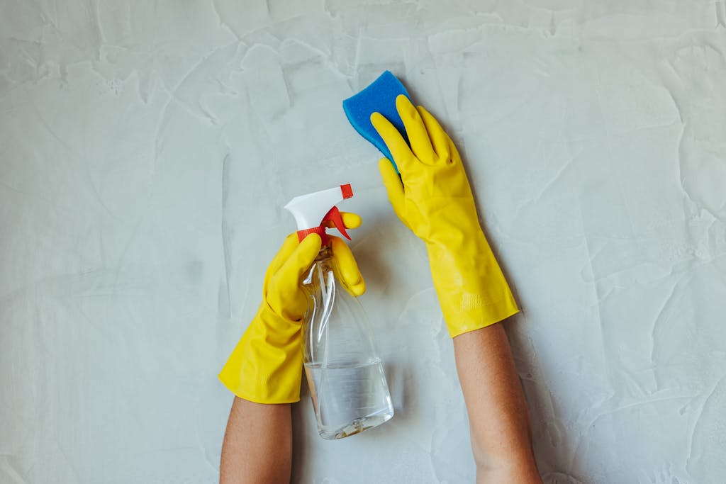 Hands Cleaning Wall with Spray Bottle and Sponge